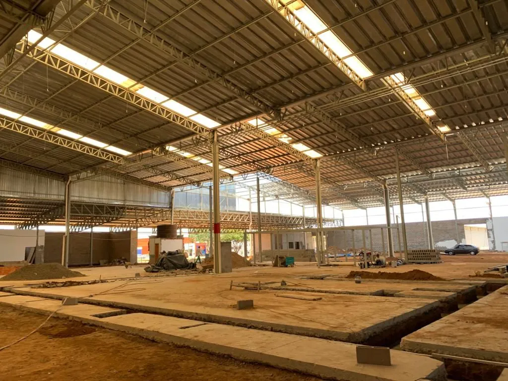 Interior de galpão logístico em construção com treliças metálicas e cobertura em telha